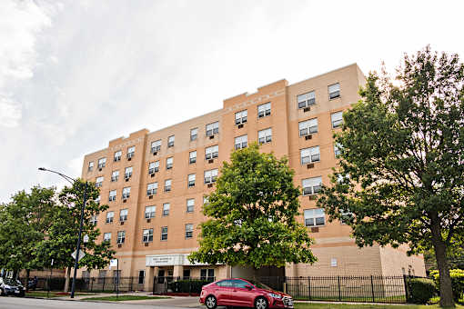 A red car is parked in front of a brick building.