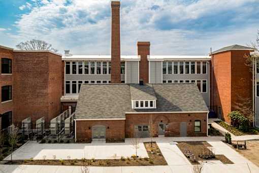 A large brick building with a smaller brick building in front of it.
