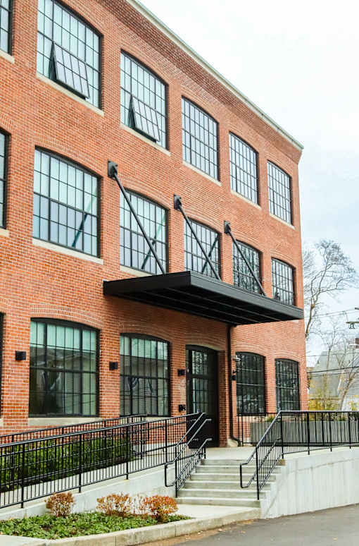 A red brick building with a black awning and a black metal fence.