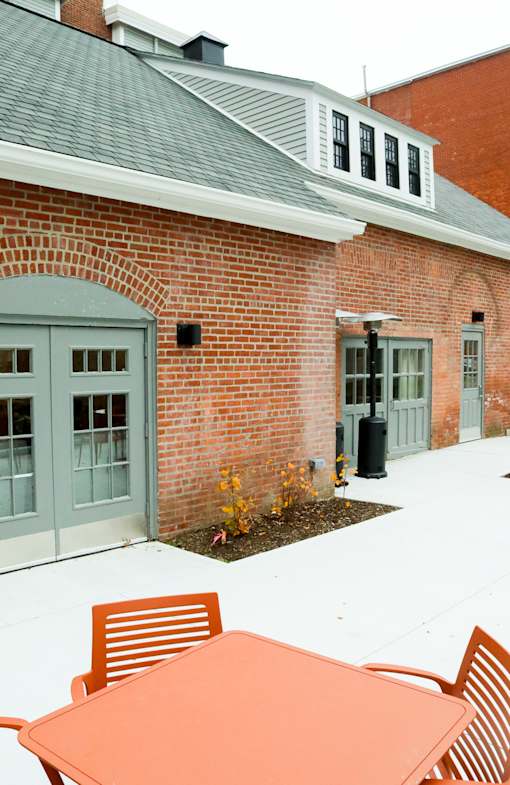 A red brick building with a grey roof and a white door.