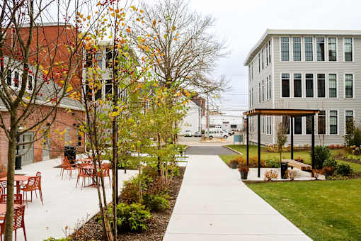 A walkway with chairs and trees in front of a building.