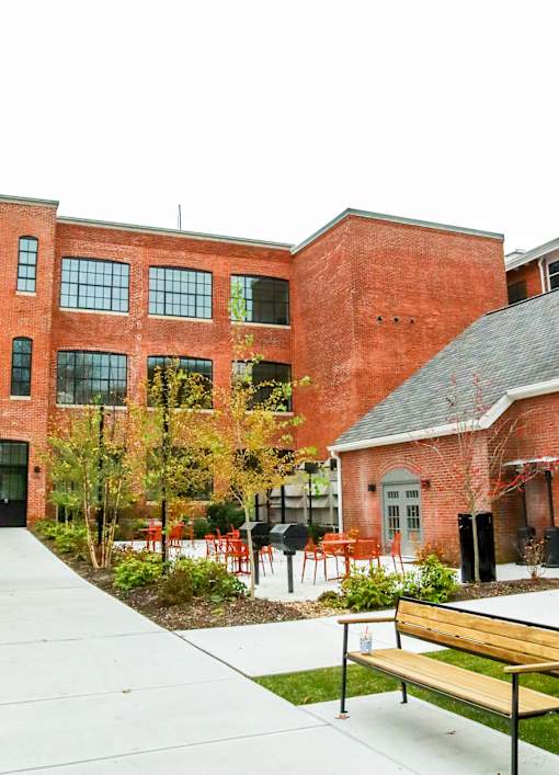 A red brick building with a bench in front of it.