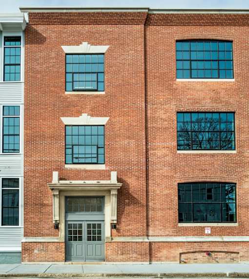 A red brick building with a grey door and windows.
