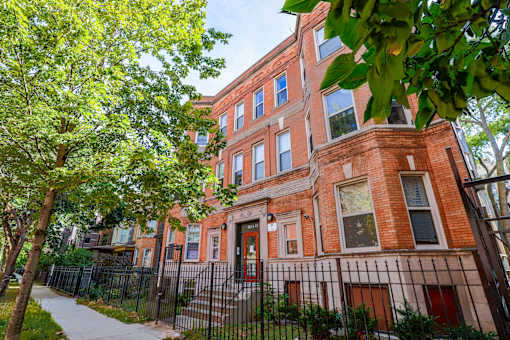 A red brick building with a black iron fence in front.