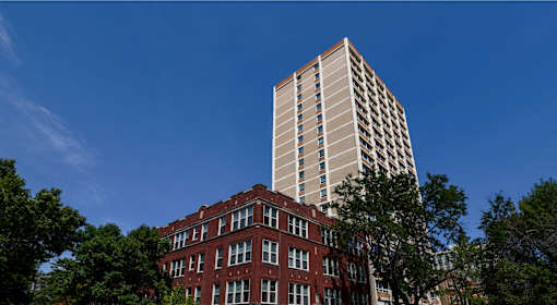 A red brick building with a tall white building behind it.