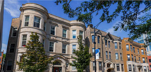 A large, old building with many windows and a flag on the front.