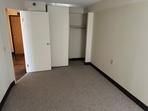 a bedroom with a carpeted floor and a closet