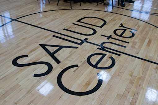 The word "Salud" is written in large black letters on a wooden floor.