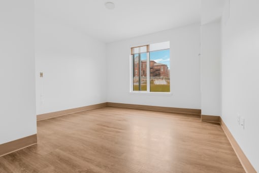 a room with white walls and wood floors and a large window
