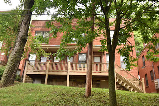 a red brick apartment building with a balcony and trees