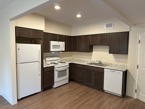 a kitchen with white appliances and dark cabinets