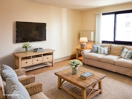 A living room with a couch, a coffee table, and a television mounted on the wall.