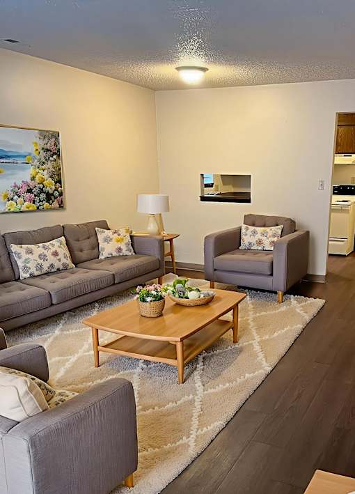 A living room with a grey couch, a wooden coffee table, and a painting on the wall.