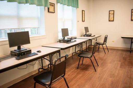 a row of desks with computers and chairs in a room