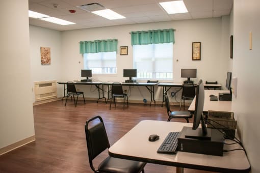 a computer room with desks and chairs and a keyboard and mouse on a table