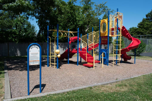 a playground with a red slide and yellow monkey bars