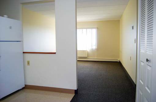 A white refrigerator sits in a room with a window and a door.