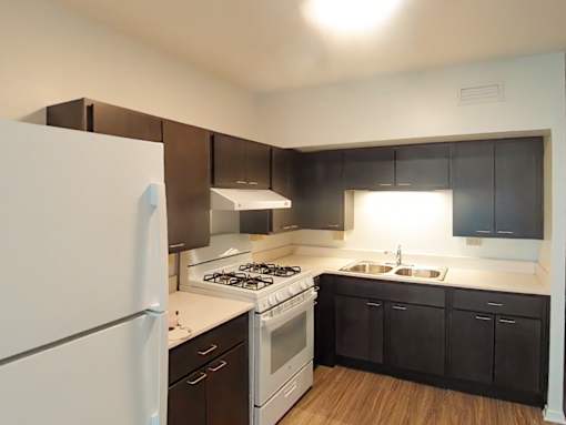 A kitchen with a white refrigerator, black cabinets, and a white stove top oven.