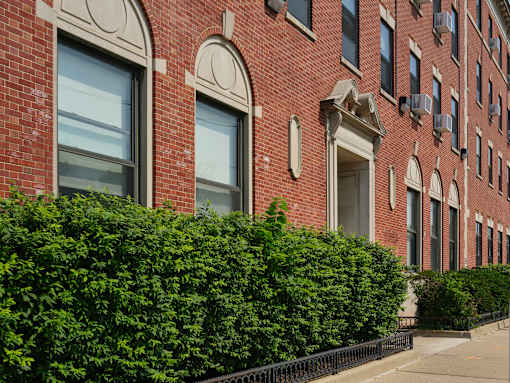 A red brick building with arched windows and a black fence.