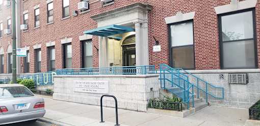 A car is parked on the street in front of a brick building with a sign that reads "Senior Center.".