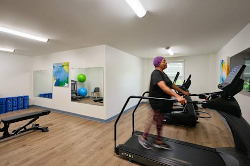 A person is running on a treadmill in a gym.