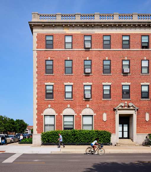 A red brick building with a balcony on the top floor.