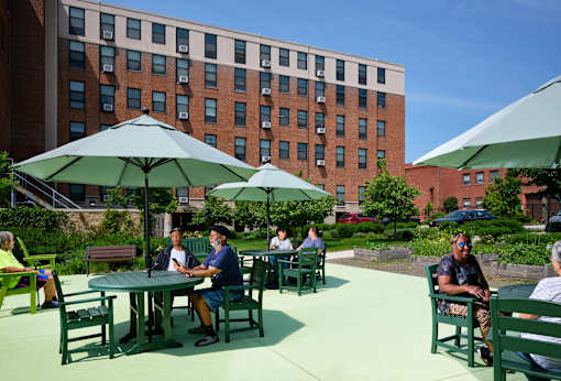 A group of people are sitting around a table under a green umbrella.