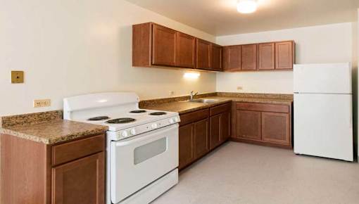 A kitchen with white appliances and brown cabinets.