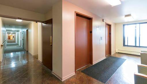 A hallway with a brown door and a grey carpet.