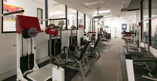 A gym with a variety of equipment including weight machines and free weights.