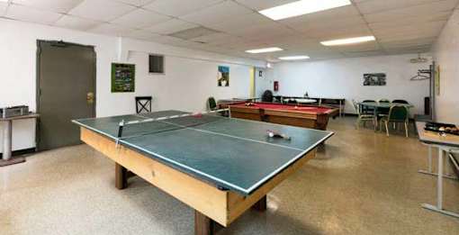 A ping pong table is in the middle of a room with a white wall and a door.