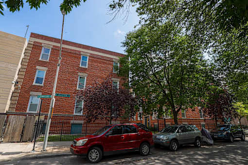 A red car is parked in front of a brick building.