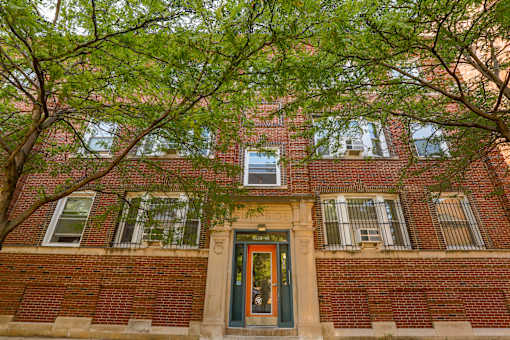 A red brick building with a green door and windows.