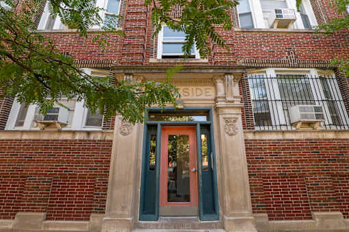 A red brick building with a green door and a sign that says "SIDE".