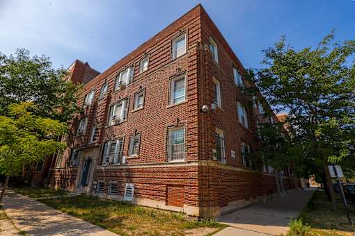A red brick building with a tree in front.