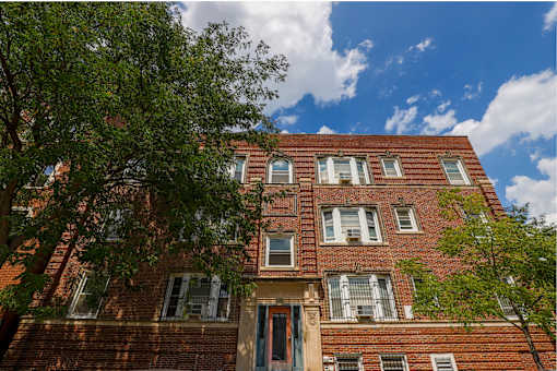A red brick building with a blue sky and clouds in the background.
