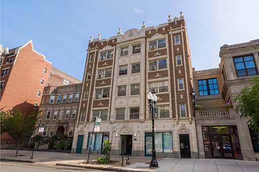 A tall building with many windows is in the middle of a street.