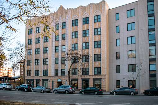 A large building with a lot of windows and cars parked in front.