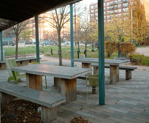 A wooden picnic table with a green chair sits on a patio.