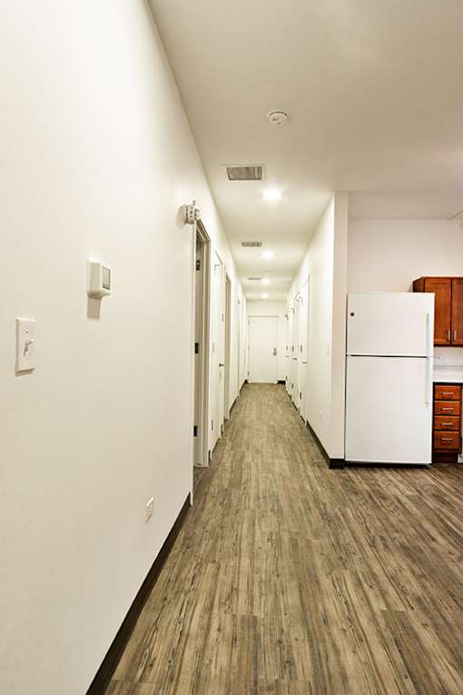 A long hallway with white walls and wood flooring.