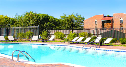 Swimming pool with sundeck, pool-side lounge chairs, and park-like setting at Inwood Apartments in La Vista, Nebraska
