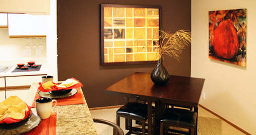 Spacious dining room with colored feature wall, and bright white kitchen with tile floor at LionsHead Apartments in Omaha, Nebraska