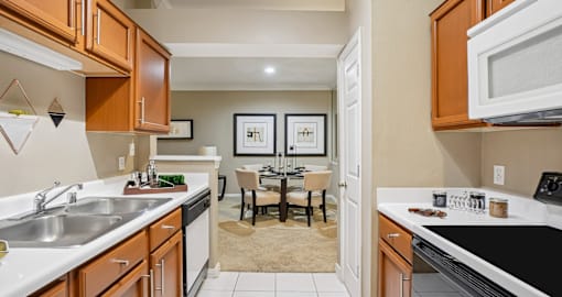 Luxury apartments with kitchens featuring honey brown toned cabinets, ample cabinet and countertop space, and spacious dining room area at Saxony Apartments in Dallas