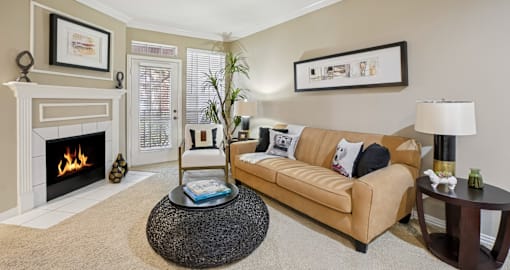 Spacious living room with wood-burning fireplace, French door, and crown molding at The Saxony Apartments in Dallas