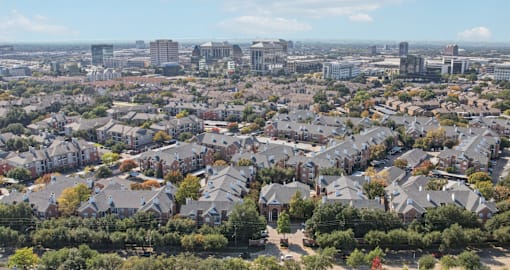 Aerial view of Saxony Apartments with view of downtown Dallas skyline and neighborhood with lots of trees