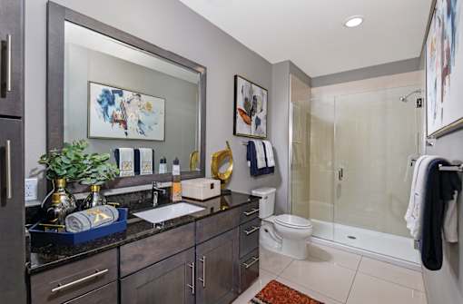 Luxury bathroom with granite countertops, glass shower and linen closet at Xenia Apartments in Golden Valley, Minnesota