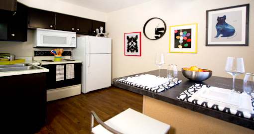 Kitchen with wood pattern floors, black kitchen cabinets, and spacious dining room at Kensington Woods Apartments in Omaha, Nebraska