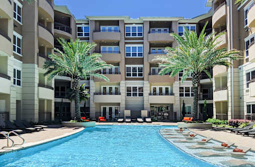Luxury apartments with resort-style pool and palm trees, fountains, lap lane, and pool-side lounge chairs at Tuscany Walk Apartments in Houston