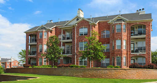 Luxury apartments with red brick exterior, spacious balconies, lush landscaping, and scenic views at Lenox Village Apartments in Lincoln, Nebraska