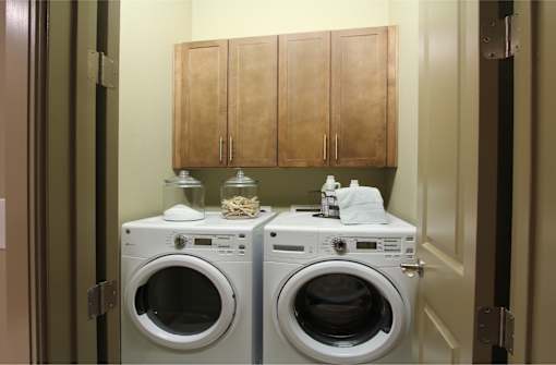 Luxury apartments with full size front loading washer and dryer with cabinet space above at Tuscany Walk Apartments in Houston.